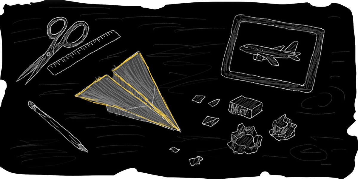 A desk with a paper airplane, and tools for creating the airplane